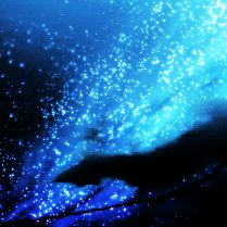 A gif of the night sky. There is a bright blue streak glittering with stars as a black cloud moves in front of it.